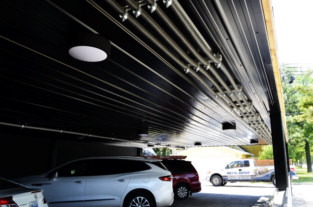 Commercial building with real wood siding, custom painted black flat panels and black ribbed cladding on parking garage ceiling